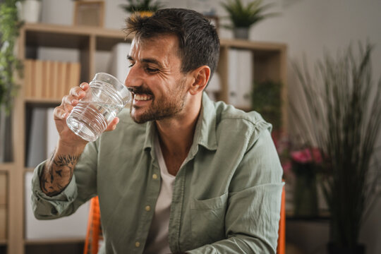 Portrait of adult handsome men sit and drink water at home