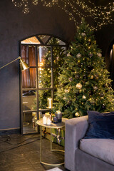 Obraz premium Christmas interior with a beautiful Christmas tree, sofa, light bulbs and dark background.