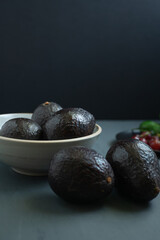 Vertical image of avocados in a bowl on a gray table.