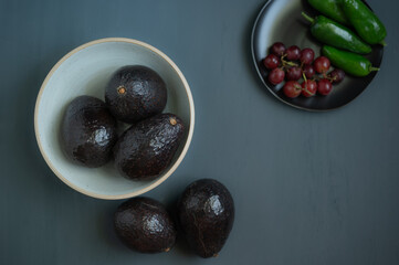 Top view of five avocados on a dark gray counter table.