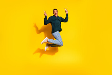Obraz premium Full body photo of nice young male jump show v-sign wear trendy green outfit isolated on yellow color background