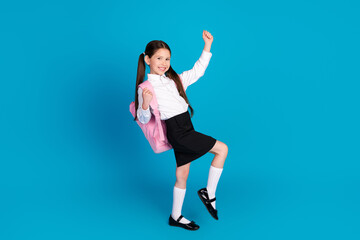 Full size photo of cute small schoolkid raise fists wear uniform isolated on blue color background