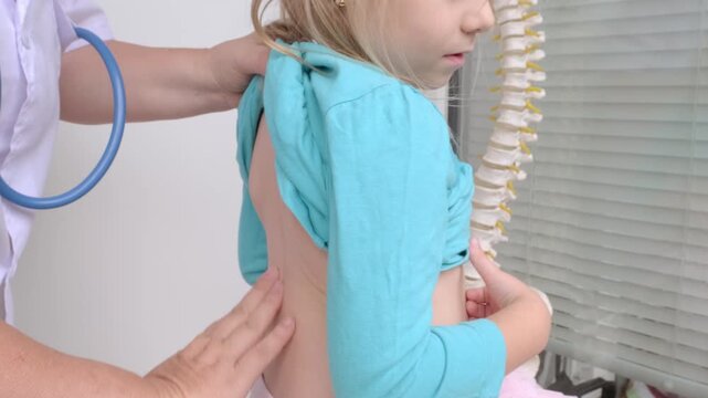 female Orthopedist doctor conducts spinal examination child, young girl shows signs scoliosis, spine deformity, healthcare provider, spine inspection, health check, spinal exam