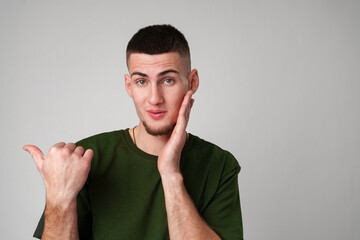 Young Man in Green T-Shirt Points to the Side