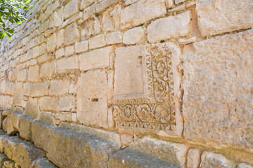 Remains of carved Roman stones, reused in the construction of modern walls.