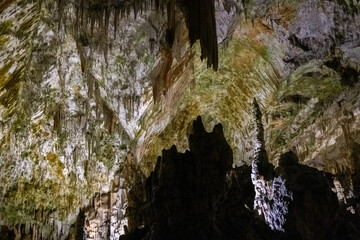 Explore remarkable stalagmite formations glowing in a vast underground cave.