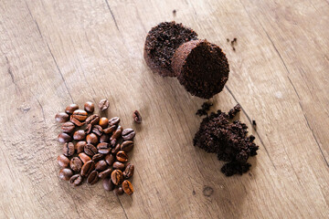 Freshly ground coffee pucks and beans arranged on a wooden surface near an automatic coffee machine.