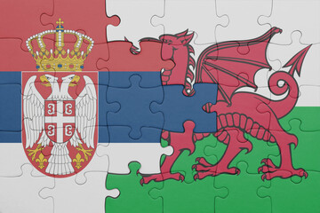 puzzle with the colourful national flag of wales and flag of serbia .