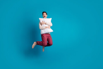 Full body photo of attractive young man jump hugging pillow dressed pajama sleepover good night...