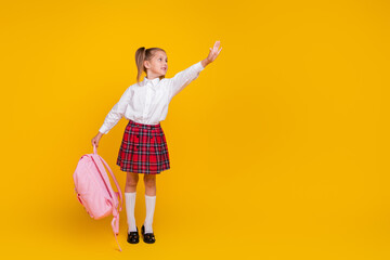 Full body photo of small schoolchild hold bag arm touch empty space wear uniform isolated on yellow...