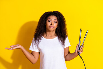 Photo of pretty young woman hair straightener shrug shoulders wear t-shirt isolated on yellow color...