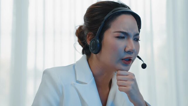 Businesswoman wearing headset working in office to support remote customer or colleague. Frustrated and tired call center customer support agent facing problem on providing vivancy service