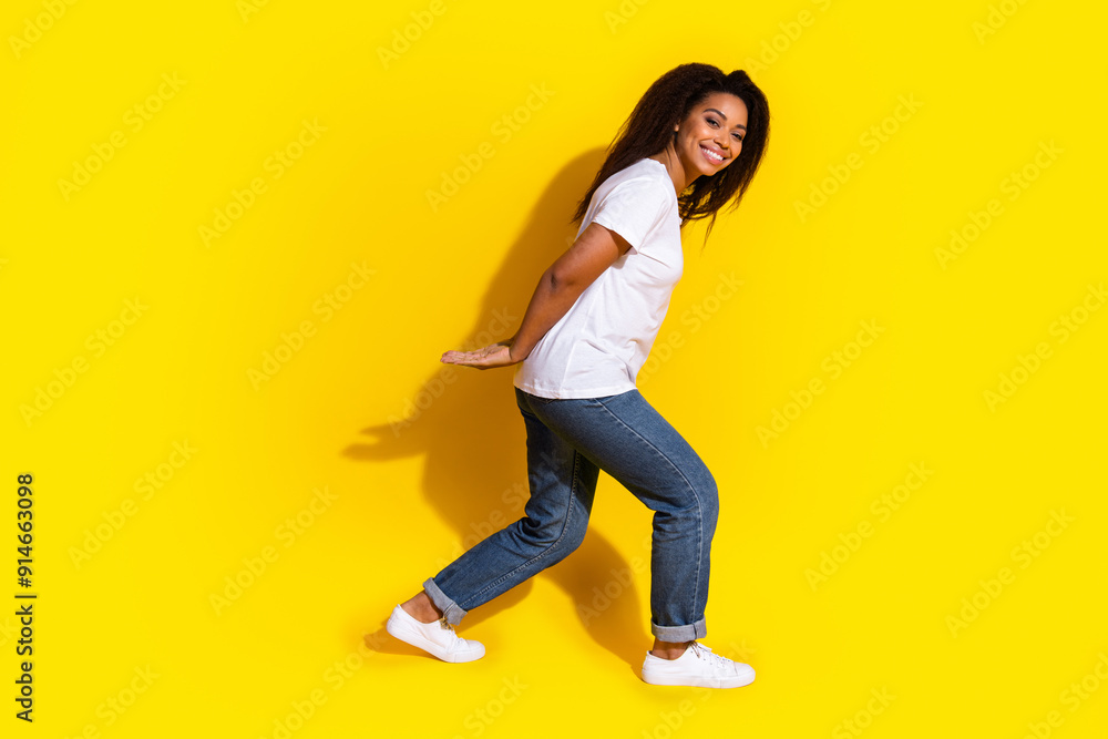 Wall mural Full size photo of pretty young woman hold empty space wear t-shirt isolated on yellow color background