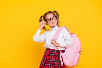 Portrait of little schoolkid touch eyeglasses wear uniform isolated on yellow color background
