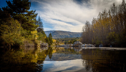 Mountain lake view with trees and vegetation surrounding the calm water mirror at San Clemente in Cordoba, Argentina