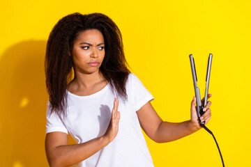 Photo of pretty young woman arm deny hair straightener wear t-shirt isolated on yellow color...