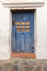 A weather blue door on a white stucco house.