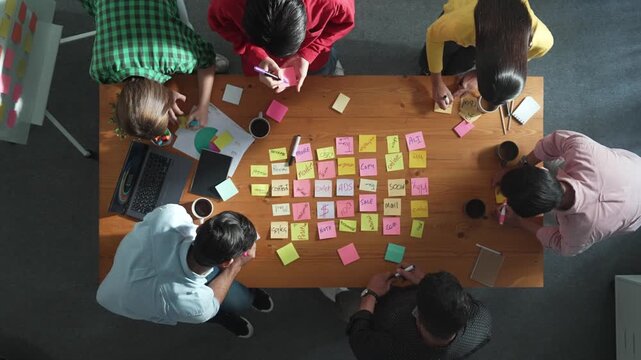 Top down view of smart diverse business people writing marketing idea at meeting and brainstorming start up project strategy or campaign at meeting room. Creative group discussing plan. Convocation.