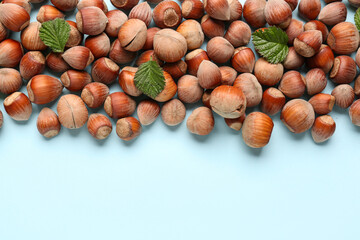 Shelled hazelnuts with leaves on blue background