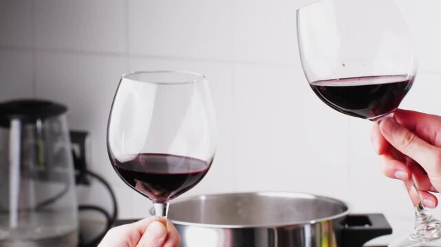 Cheers glasses of red wine, Romantic couple enjoying wine and cooking dinner at home, concept love, relationship and romantic, happy couple celebrating and making cheers with glasses of red wine