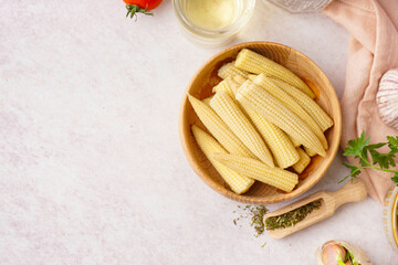 Bowl with canned baby corn cobs on light background