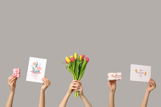 Women with gifts, drawings and tulips on light background. Mother's Day celebration