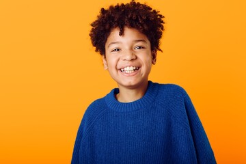 Radiant young african american boy beaming with joy in a vibrant blue sweater against a bright...