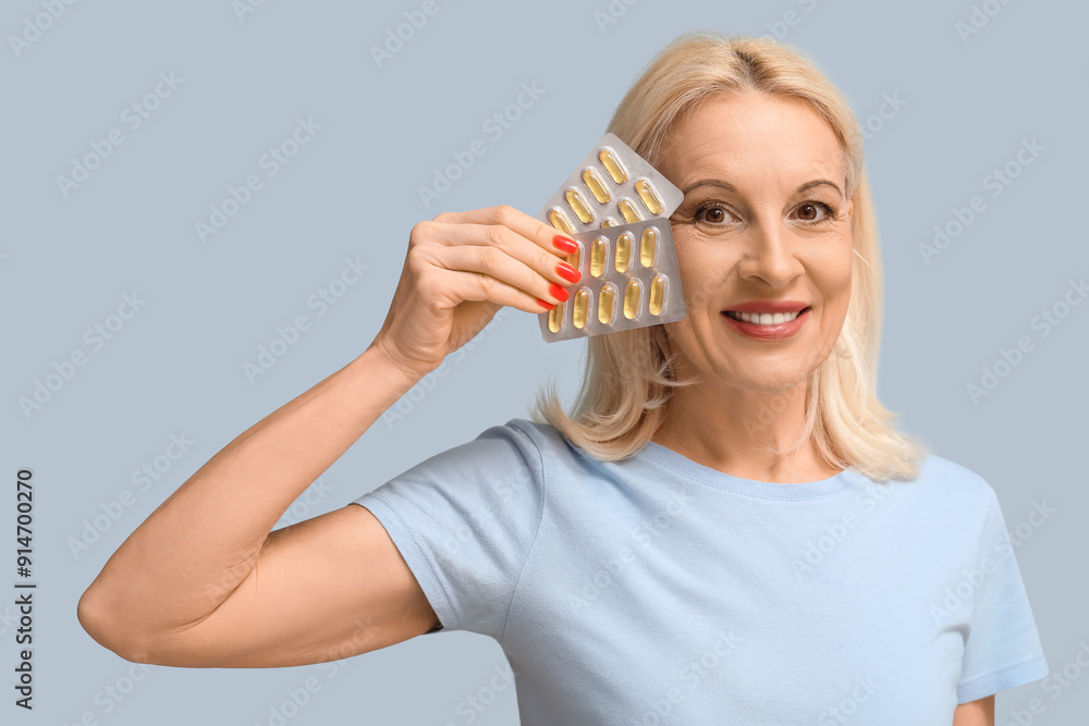 Poster Mature woman with fish oil pills on light blue background