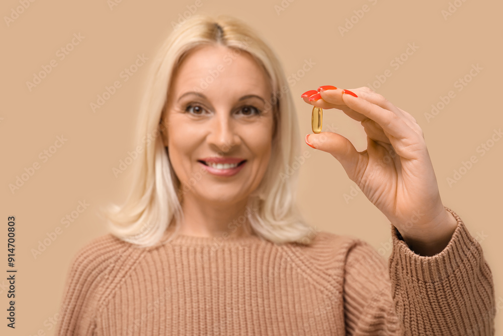 Sticker Mature woman with fish oil pill on beige background