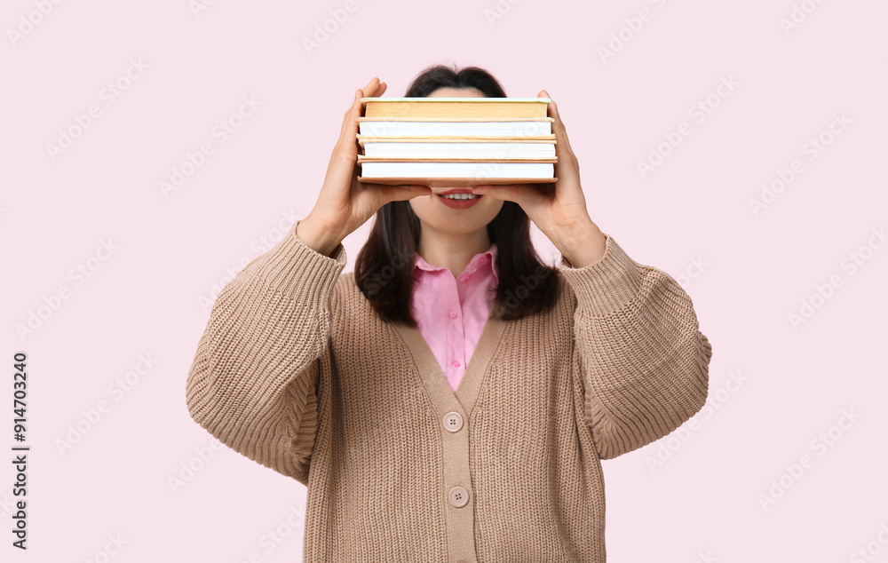 Wall mural young woman holding books on pink background