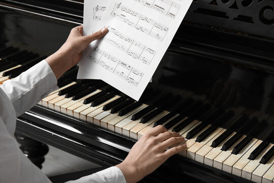 Young woman playing piano with note sheet