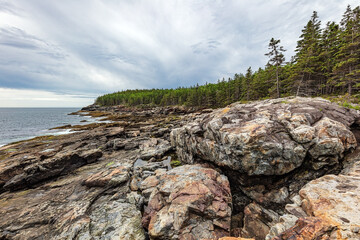 Rocky shoreline, forest and storm clouds in Acadia National Park Desert Island Maine, USA 