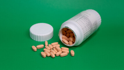 pills and bottle on green background