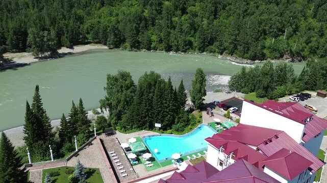 Cold mountain river Katun in the Altai mountains, hotel "Korona Katuni" on an island in the middle of the river, drone view