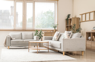 Stylish interior of living room with grey sofas, window and coffee table