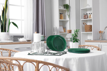 Set of clean dishes and glasses on dining table in kitchen