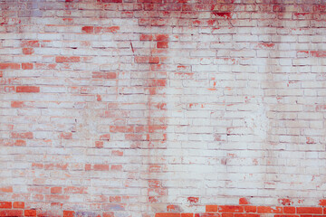 Old grungy red brick wall. Free space for an inscription. Fragment of a wall with bumps and peeling paint.