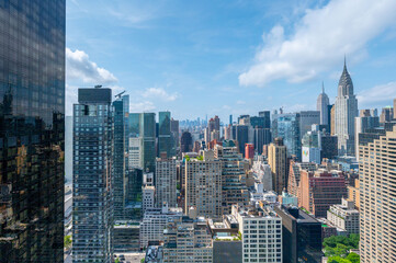 Fototapeta premium Vibrant view of New York City's skyline featuring a mix of modern and classic skyscrapers. Highlights the city's architectural diversity and bustling urban environment under a clear blue sky. 