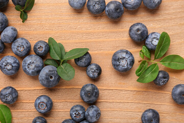 Sweet fresh blueberries and leaves on wooden background