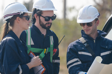 A team of engineers sitting in a van is inspecting the construction of a wind turbine and surrounding structures in a remote area to produce clean electricity.