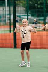 Obraz premium A smiling young girl in casual sports attire exercises on a green sports field, demonstrating joy and energy in a physical activity event.