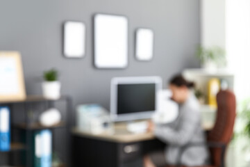 Female office worker using modern computer at workplace in stylish office, blurred view