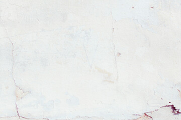 White plaster wall with natural defects. Fragment of the grunge surface. Natural cracked cement on a light wall. Textured background for integration into the design.