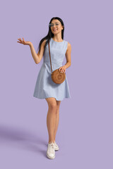 Young woman in eyeglasses with bag on lilac background