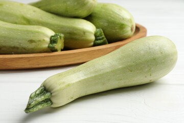 Raw green zucchinis on white wooden table, closeup