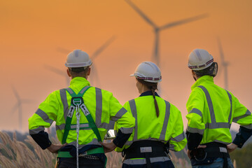 Fototapeta premium Team Engineers men and woman checking and inspecting on construction with sunset sky. people operation. Wind turbine for electrical of clean energy and environment. Industrial of sustainable.