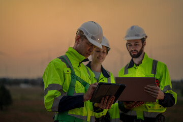 Team Engineers men and woman checking and inspecting on construction with sunset sky. people operation. Wind turbine for electrical of clean energy and environment. Industrial of sustainable.