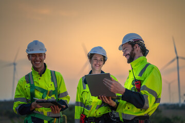 Team Engineers men and woman checking and inspecting on construction with sunset sky. people operation. Wind turbine for electrical of clean energy and environment. Industrial of sustainable.