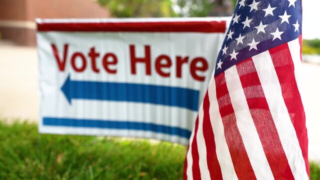 vote here sign blurred with American flag in focus at polling place precinct