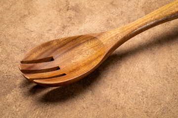 spork, spoon and fork combination - wooden kitchen cooking utensils on textured bark paper